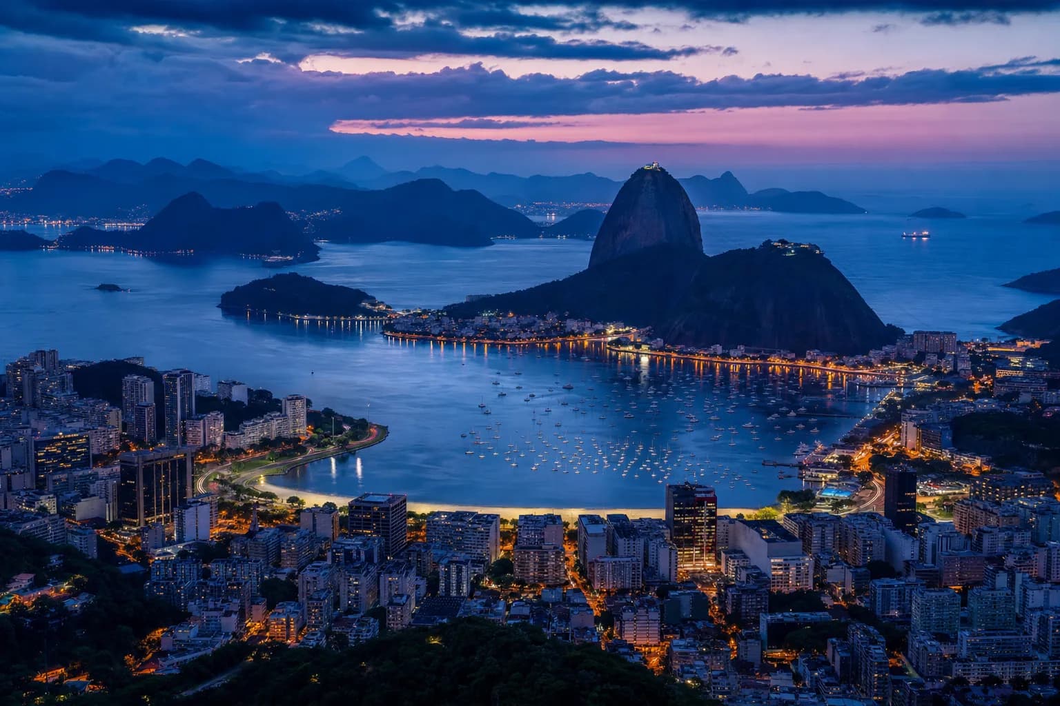 Vista do Pão de Açúcar e da Baía de Guanabara ao entardecer, com o Rio de Janeiro ao fundo