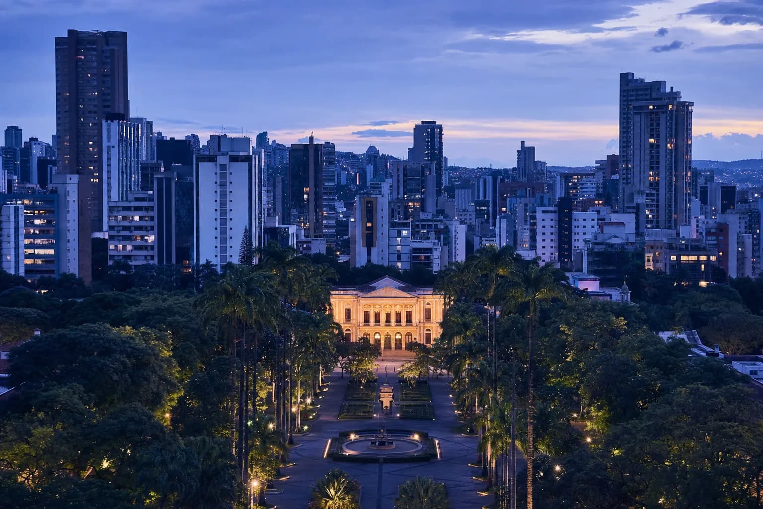 Vista de Belo Horizonte no fim de tarde, com a Praça da Liberdade em primeiro plano e os prédios da Savassi ao fundo
